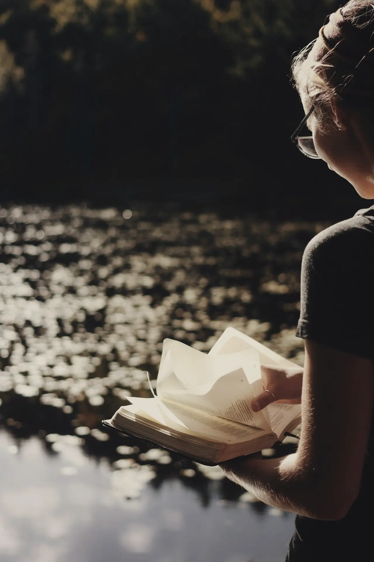 woman in black crew neck t-shirt and black framed eyeglasses holding white paper